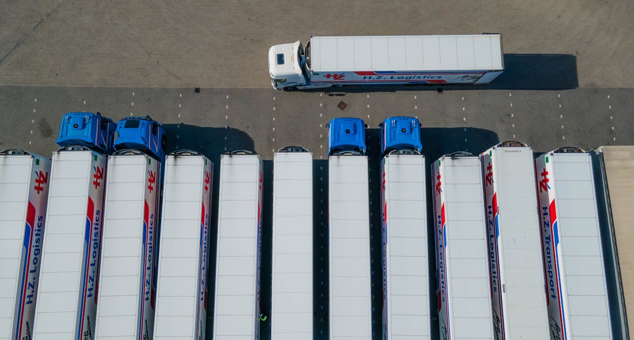 creative-02 Top-down drone shot of logistics trucks arranged in a row in a parking lot.